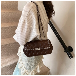 Detail view of dark brown quilted chain crossbody bag with silver clasp on model