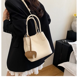 Détail du sac seau en cuir grainé crème avec une breloque éléphant marron mignonne
