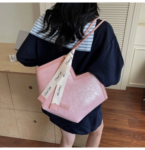 Detail view of pink pleated tote bag with decorative branded ribbon and glossy finish