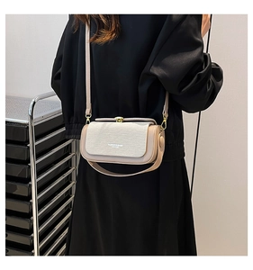 Detail view of beige crossbody bag with textured fabric, gold buckle and leather strap