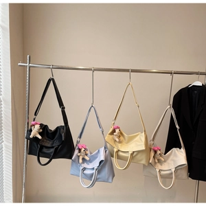 Detalle de bolsos tote de cuero multicolor con colgantes de perro y correas anchas