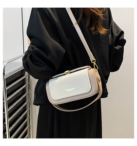 Detailed view of cream-colored patchwork shoulder bag with woven texture and gold clasp