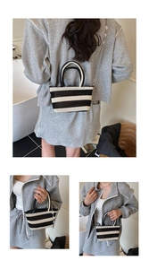 Detail of black and white striped woven tote bag featuring floral metal chain strap