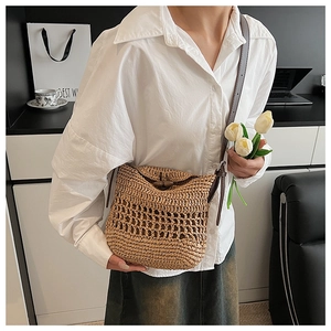 Detail of straw woven crossbody bag featuring wood button closure and leather strap