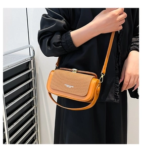 Detail of a contrast leather crossbody bag with textured stitching and gold hardware