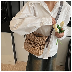 Detail of hand-woven straw crossbody bag with brown leather strap and hollow texture
