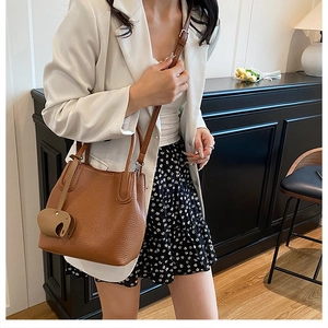 Sac seau marron en cuir avec breloque éléphant porté avec un blazer élégant