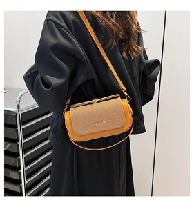 Detail of orange crossbody bag featuring brown woven texture flap and gold metal hardware
