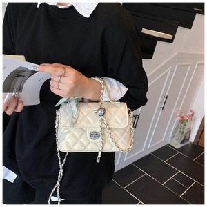 Detailed view of white quilted crossbody bag with golden chain strap and silk scarf