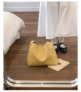 Vista dettagliata della borsa tote in pelle gialla con trama naturale su pavimento a specchio