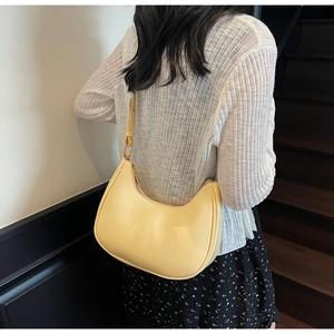 Pale yellow hobo bag shown on model highlighting the half-moon shape and shoulder fit