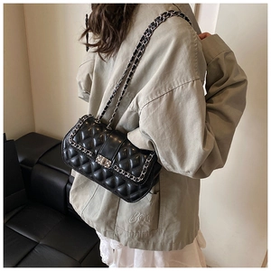 Detail of black quilted leather crossbody bag with silver chain strap and metal clasp