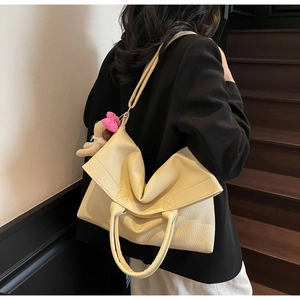 Detalle del bolso tote de cuero granulado blanco crema con cierre plegado asimétrico