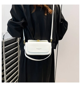 Detail of white leather crossbody bag with golden hardware and fashion logo text