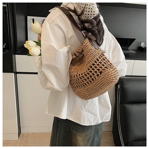 Detailed back view of a handwoven straw backpack with brown leather straps and metal buckles
