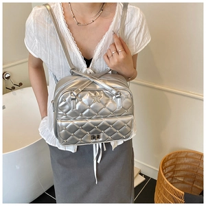 Detail of silver quilted backpack with star diamond logo and metallic finish