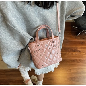 Detail of pink quilted bucket bag with silver studs and polished patent leather finish