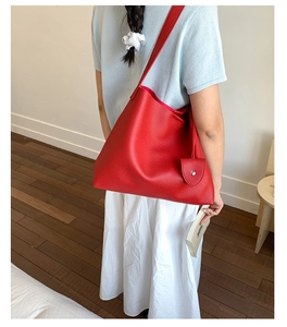 Dettaglio della borsa tote in pelle martellata rossa con ciondolo a forma di cuore laterale