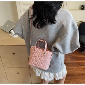 Detail of pink quilted bucket bag with silver studs worn by model in a casual setting
