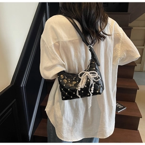 Détail du sac matelassé noir avec nœud en dentelle et chaîne de perles sur modèle