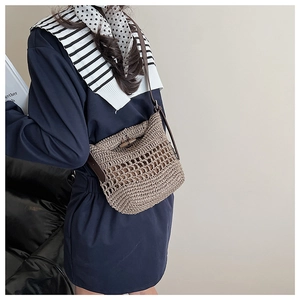 Detail of straw woven bag featuring a rustic wooden toggle closure and leather strap
