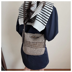 Detail of khaki straw crochet crossbody bag with brown leather strap and wooden buckle