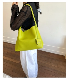 Borsa tote verde lime con ciondolo a cuore indossata da modella in stile minimal
