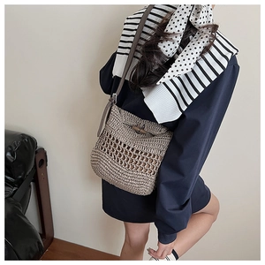 Detail showing the intricate woven texture and leather strap of the straw shoulder bag