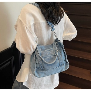 Detailed back view of a light blue washed denim crossbody bag worn over a white shirt