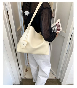Vista posteriore della modella con borsa tote grande in pelle martellata color crema