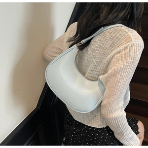 Side view of a light blue crescent shoulder bag with minimalist matte leather finish
