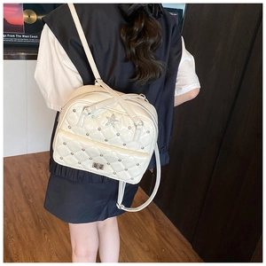 Detail of cream quilted leather backpack with star emblem and metal rivet accents