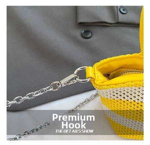 Close-up of silver metal clasp and chain strap on striped woven handbag detail