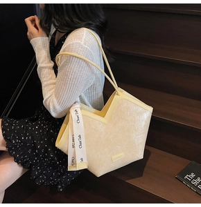 Close-up of beige tote bag with crinkle texture and branded wide fabric strap