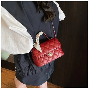 Close-up of red quilted crossbody bag with floral scarf handle and metallic lock