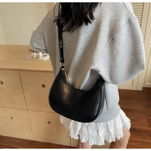 Close-up of minimalist black hobo bag with sleek matte leather and metal zip detail