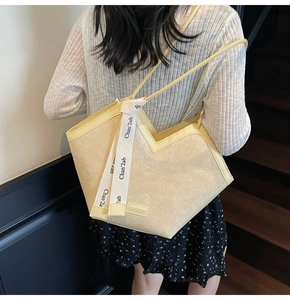 Detail of cream large tote bag with V-shaped opening and stylish branded ribbon accent