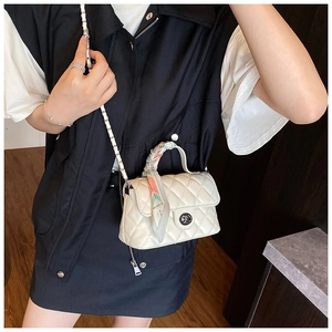 Detail of cream quilted crossbody bag with silk scarf wrapped around handle