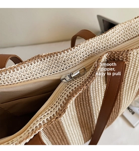 Detail of a striped straw tote bag showing the smooth zipper closure and woven texture