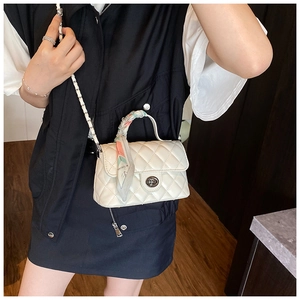 Macro detail of white quilted chain bag with patterned scarf handle and metal clasp