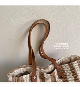 Detail of durable brown leather handles and metal rivets on the striped straw tote bag