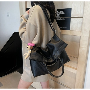 Detalle de bolso tote de cuero granulado negro con un lindo colgante de perro de peluche