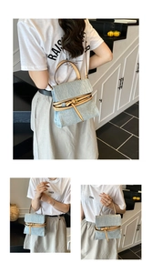 Detail of light blue denim handbag featuring brown leather handles and buckle belt design
