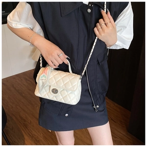 Detail of off-white quilted crossbody bag with silver twist lock and woven strap
