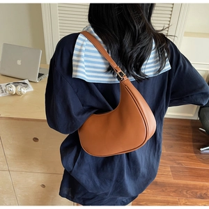 Brown leather hobo shoulder bag shown on model with minimalist high-end aesthetic