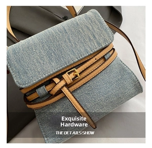Close-up of blue denim flap bag with brown leather straps and gold buckle detail