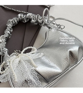 Détail du sac froissé argenté avec nœud en dentelle perlée et bandoulière chaîne