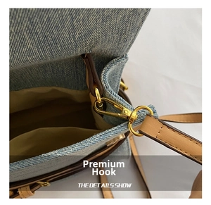 Close-up of golden metal swivel hook and brown leather strap on blue denim handbag
