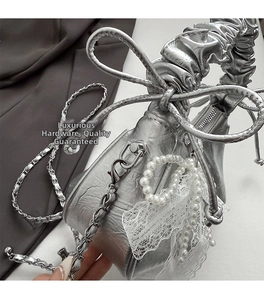 Détail du sac argenté métallisé avec poignée à froufrous, chaîne et breloques en perles et dentelle