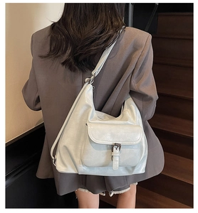 Detailed view of fashionable silver tote bag with buckle flap pocket worn by a model